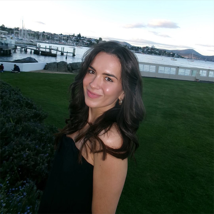 Woman with dark hair smiling outdoors near waterfront, relating to woman stunned by hinge match on first date. Woman with dark hair smiling outdoors near waterfront, relating to woman stunned by hinge match on first date.