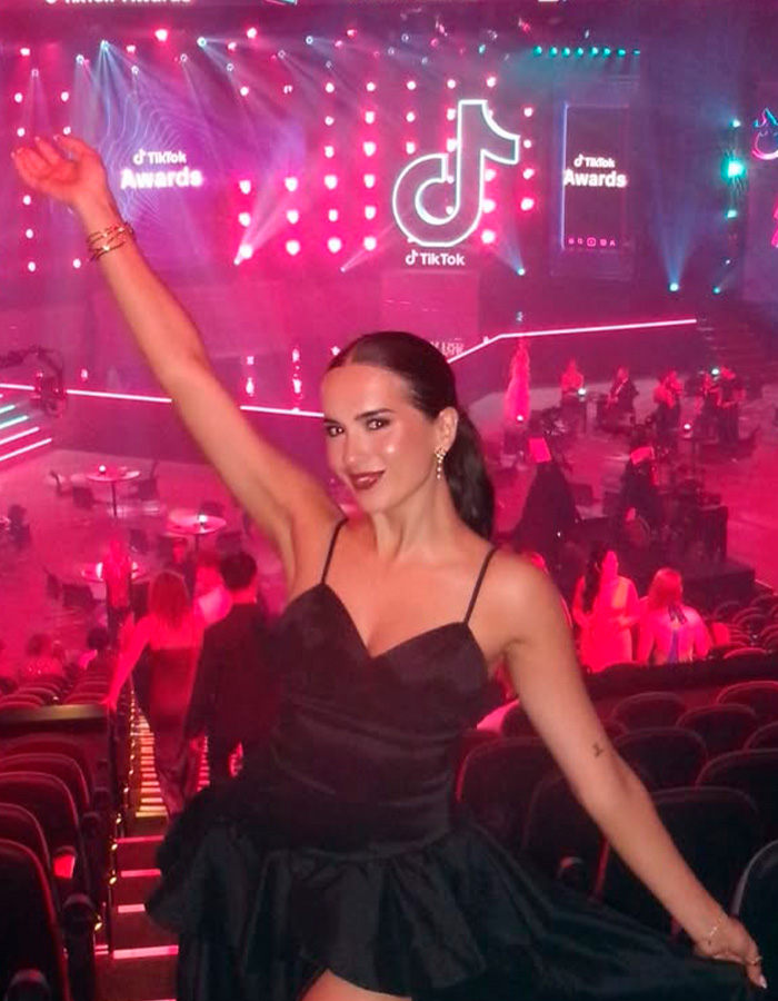 Woman in black dress celebrating at TikTok Awards event with colorful lights in the background, tied to Hinge match first date story. Woman in black dress celebrating at TikTok Awards event with colorful lights in the background, tied to Hinge match first date story.