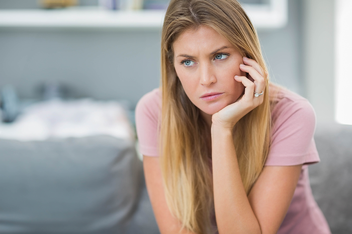 Daycare worker looking thoughtful and concerned, sitting indoors, reflecting on a passive-aggressive coworker gift incident Daycare worker looking thoughtful and concerned, sitting indoors, reflecting on a passive-aggressive coworker gift incident