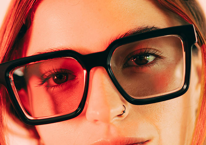 Close-up of a woman wearing large black glasses, highlighting what women obsess over according to 48 men’s perspectives.