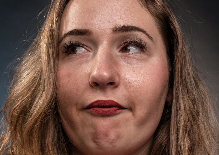 Close-up of a woman making a thoughtful face, illustrating what women obsess over for no reason according to 48 men.
