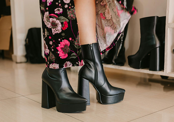 Black platform ankle boots worn with a floral dress, highlighting fashion women obsess over for no reason.
