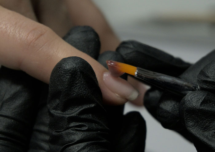Close-up of a nail technician applying polish to a customer's nails, highlighting what women obsess over.