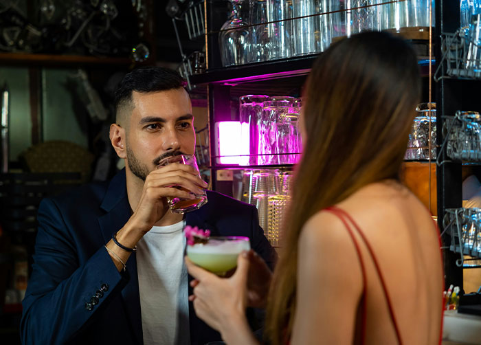 Man and woman at a bar having drinks, illustrating what women obsess over for no reason according to men.