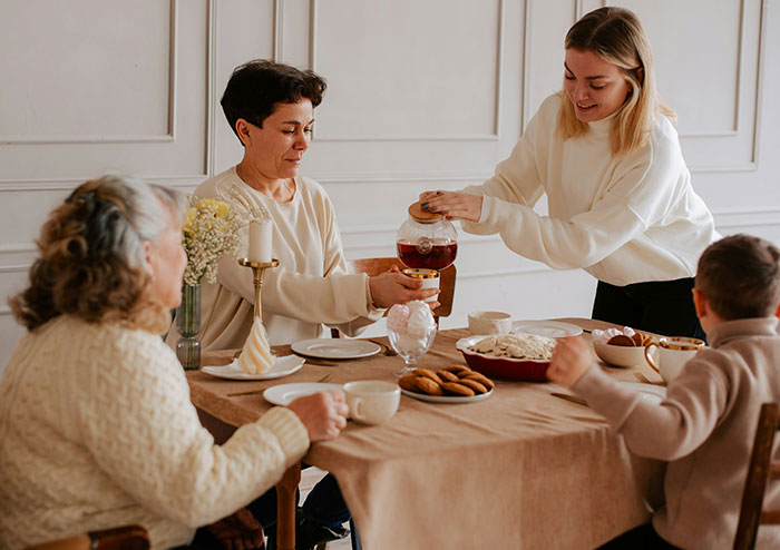 Four people gathered around a table sharing tea and cookies, highlighting what women obsess over for no reason.