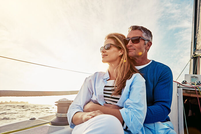 Couple wearing sunglasses relaxing on a boat at sunset, reflecting on misconceptions about women in modern times.