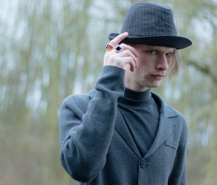 Young man wearing a striped fedora and gray sweater outdoors, symbolizing misconceptions about women men need to put to rest.