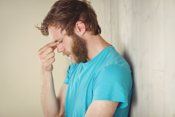Man in blue shirt leaning against wall with eyes closed, reflecting on misconceptions about women and modern perspectives.