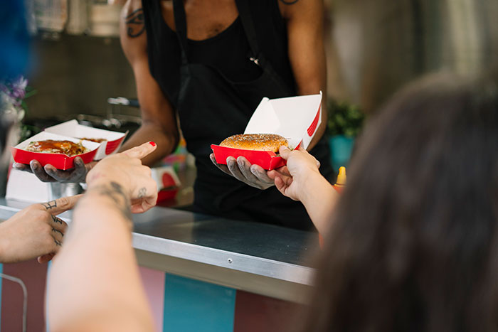Server handing out burgers to customers with visible frustration, illustrating servers sharing customer horror stories.