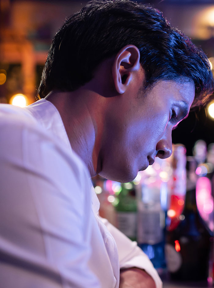 A server leaning on the bar, looking stressed and overwhelmed by difficult customer horror stories at work.