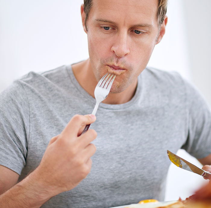 Man tasting food with a fork, reflecting on a possible customer horror story related to servers and dining experiences.