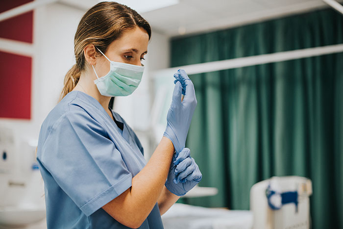 Female healthcare worker wearing a mask and gloves preparing for medical care for heartbreaking medical conditions patients