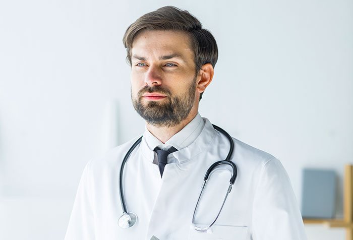 Bearded male doctor with stethoscope in white coat looking thoughtful, representing heartbreaking medical conditions that can't be cured