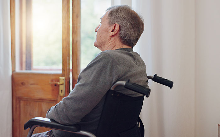 Elderly man in a wheelchair sitting indoors by a window, representing heartbreaking medical conditions that can’t be cured.