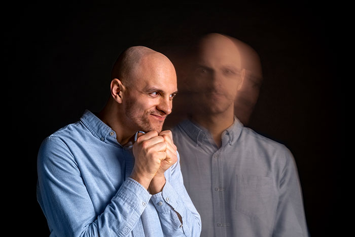 Man in blue shirt showing anxious hands with blurred double exposure effect, representing heartbreaking medical conditions.