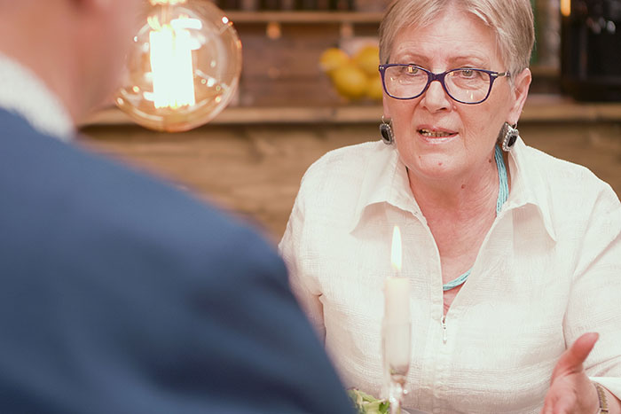 Older woman wearing glasses, engaged in a serious conversation over dinner, representing 20 MILs that won the absolute worst.