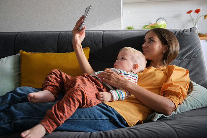 Woman and child relaxing on sofa looking at smartphone, illustrating 20 MILs that won the absolute worst in January.