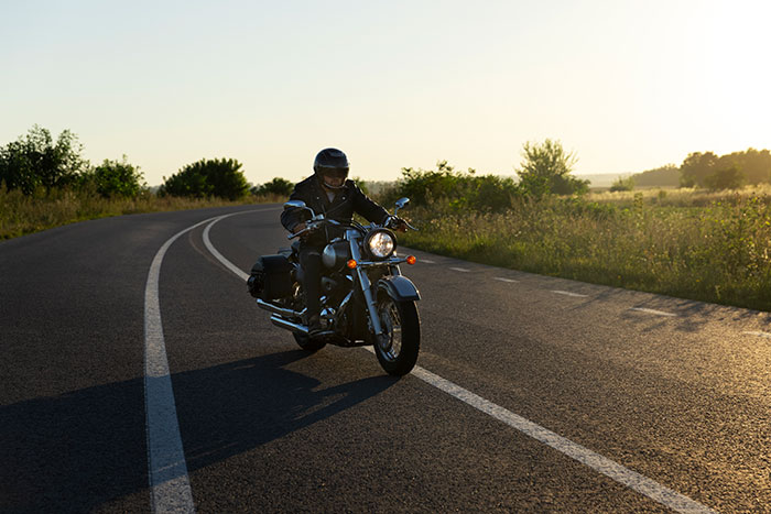 Motorcyclist riding on a winding road at sunset, illustrating one of the lucky times people got out of danger.