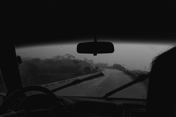 View from inside a car driving in heavy rain, showing windshield wipers clearing water for safe and lucky escape moments.