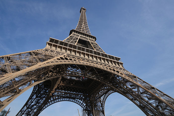 View looking up at the Eiffel Tower against a clear blue sky, illustrating lucky times people escaped danger.