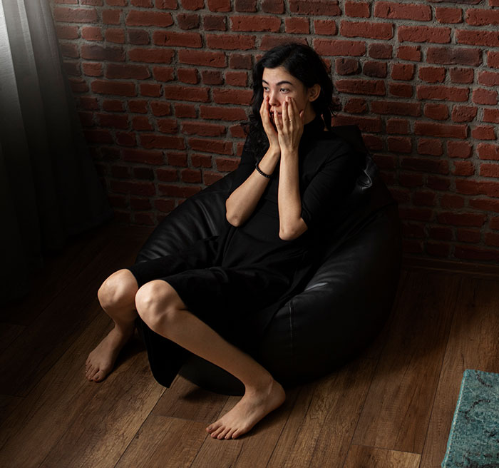 Woman in black dress sitting on a bean bag chair looking worried, representing lucky times people got out of danger.
