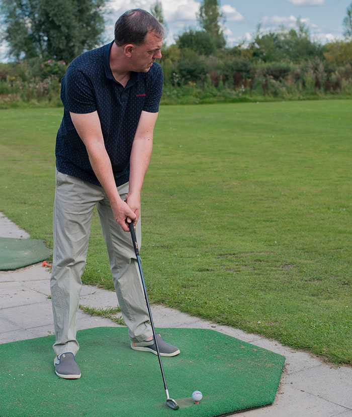 Man preparing to play golf on a green mat, illustrating lucky times people got out of dangerous situations.