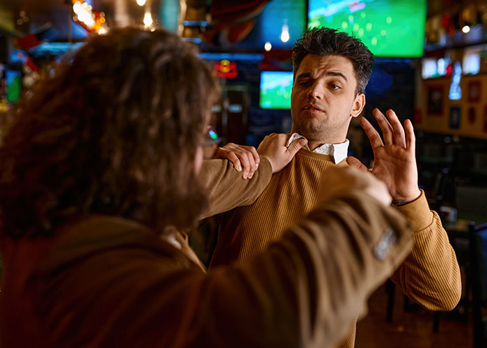 Two men in a bar involved in a tense altercation, illustrating people being in the wrong place at the wrong time.