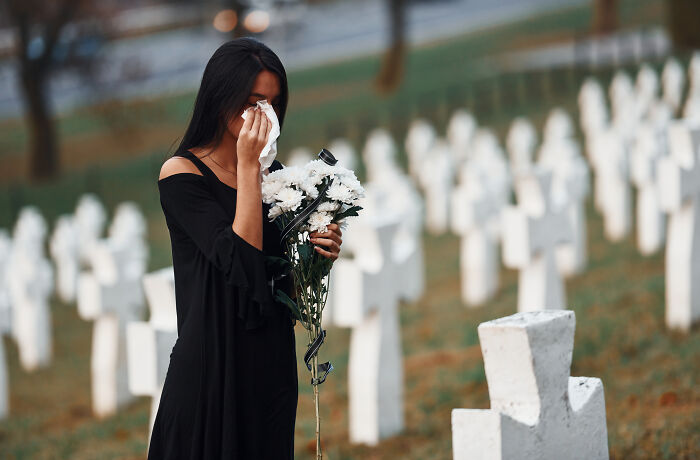 Woman holding flowers and crying at a cemetery, reflecting on moments people realized they no longer wanted to work.