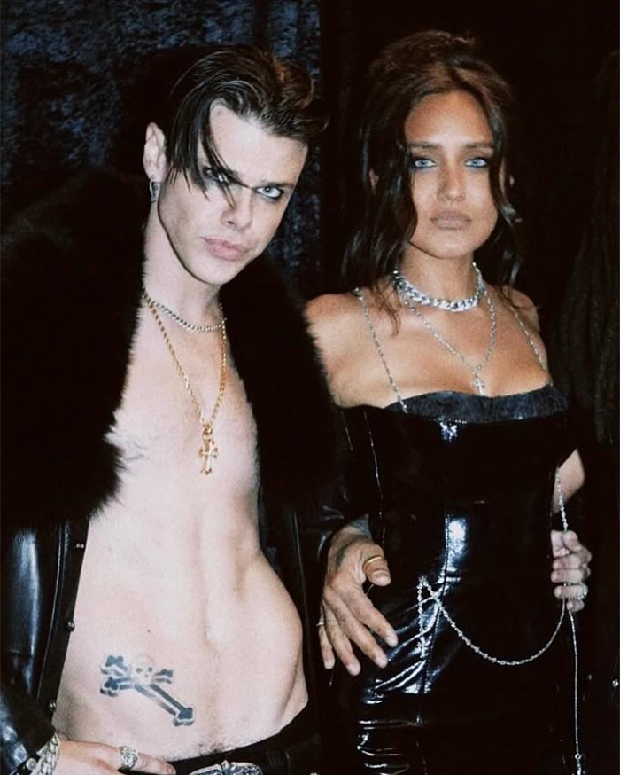 Unclothed rock star Yungblud posing with a woman dressed in black at a wild Sydney yacht party event.