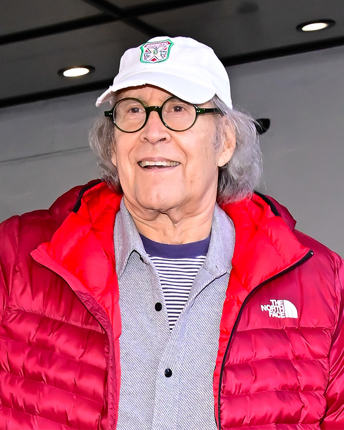 Older man wearing a white hat and red jacket smiling, related to Chevy Chase N-Word scandal and Community actress documentary. Older man wearing a white hat and red jacket smiling, related to Chevy Chase N-Word scandal and Community actress documentary.