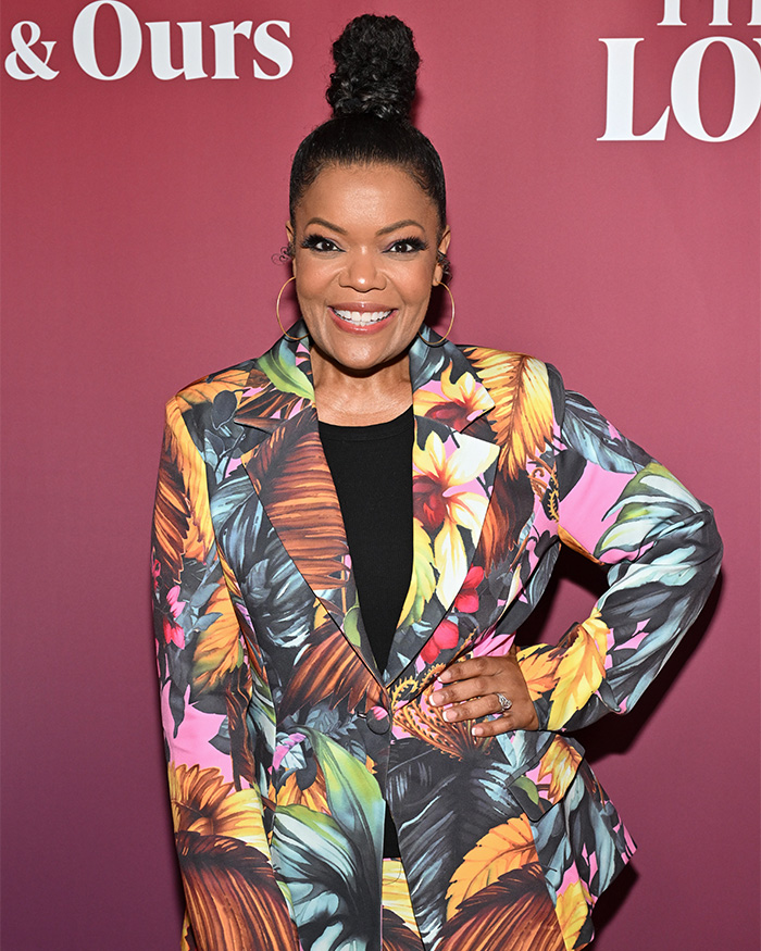 Community actress smiling at event, wearing colorful floral blazer, related to Chevy Chase's N-Word scandal discussion.