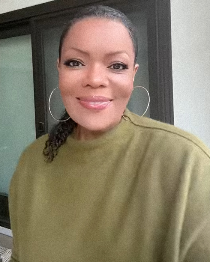 Community actress wearing hoop earrings and an olive green top discusses Chevy Chase N-Word scandal in documentary.