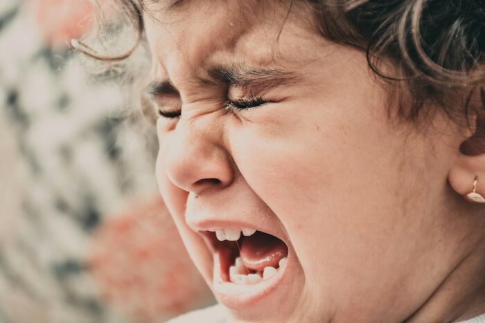 Close-up of a young child crying in distress, illustrating emotional impact of a doctor doing something unethical with a patient.