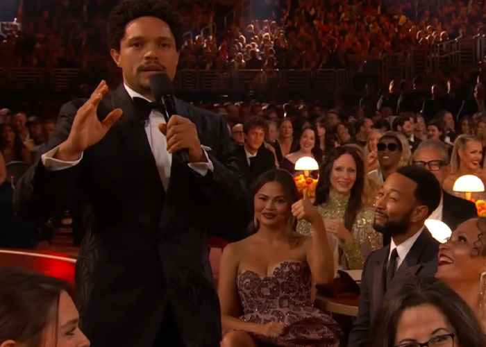 Trevor Noah speaking at the Grammys, wearing a tuxedo, as audience reacts to his bizarre Grammys statement.