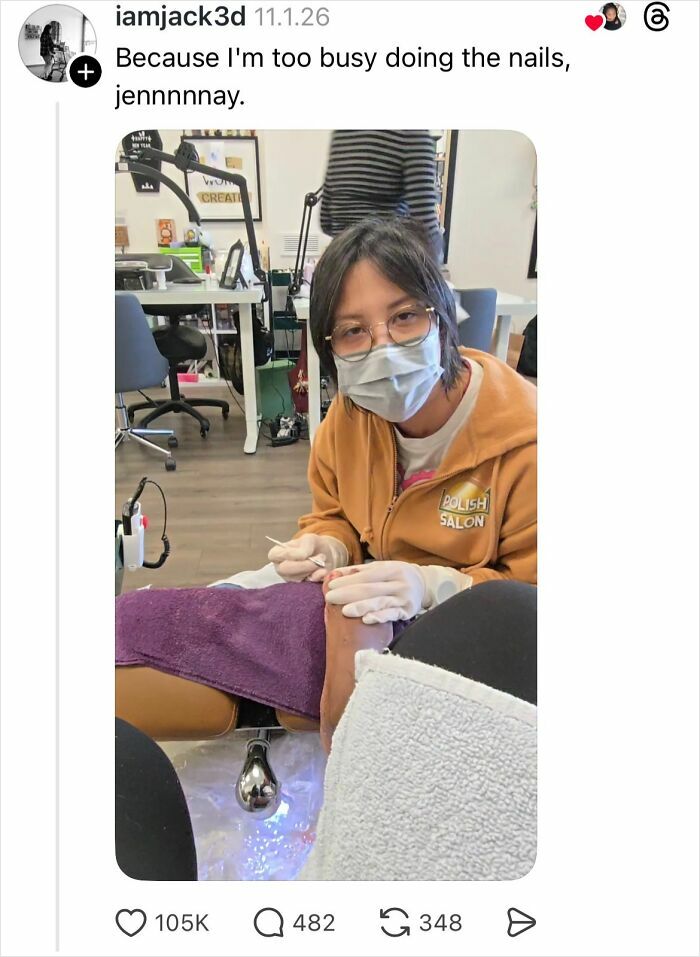 Woman getting nails done at a salon with a technician wearing a mask and gloves, busy polishing nails.