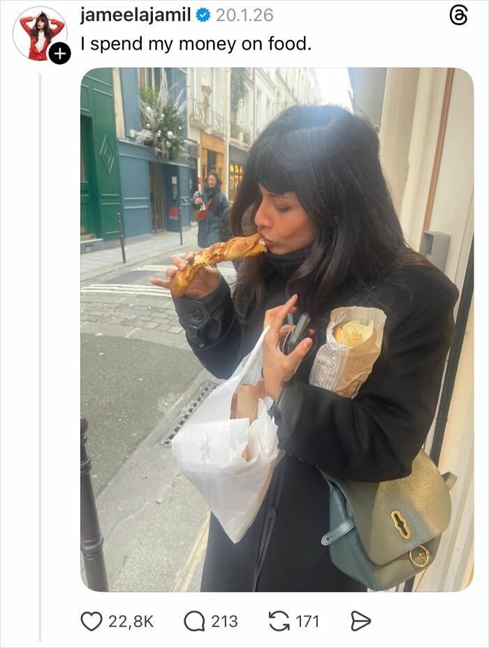 Woman eating bread on street, holding bags and phone, illustrating why girls don’t get their nails done discussion.