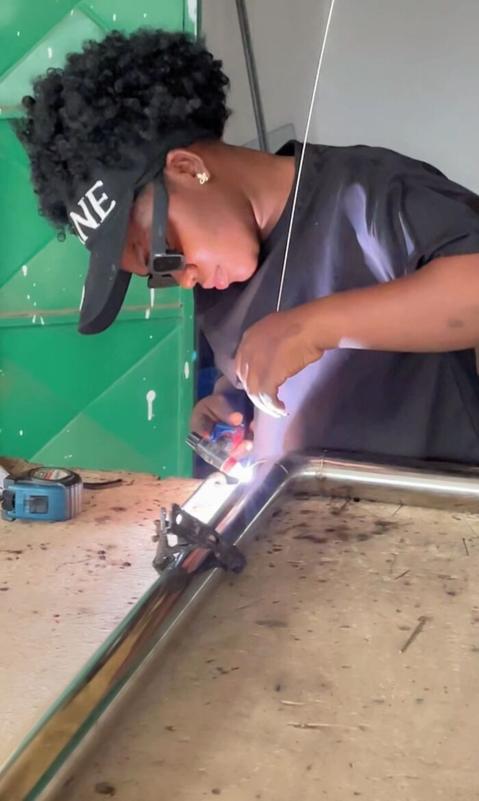 Woman concentrating while welding metal, highlighting nails during hands-on work and craftsmanship.