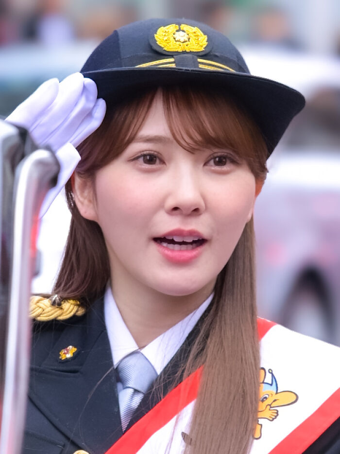 Shiho Katō wearing a formal uniform and hat, saluting during a public event or parade.
