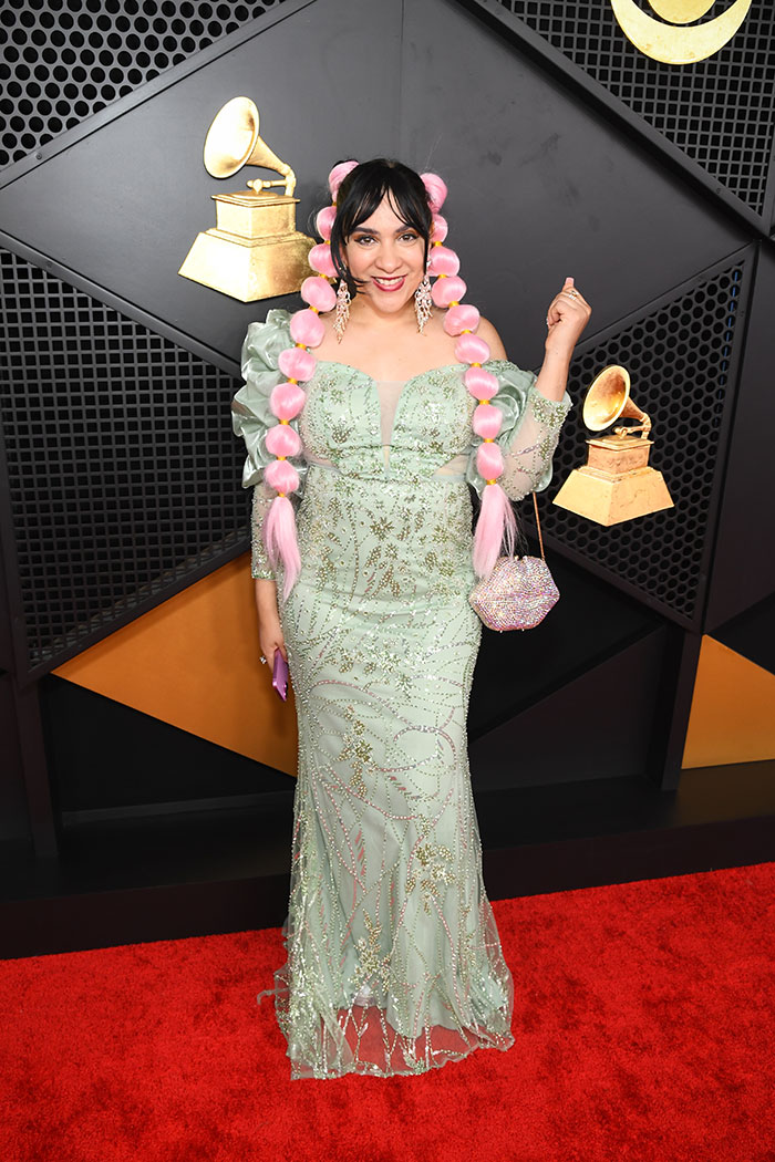 Woman with elaborate pink braided hair and green embellished gown posing on the 2026 Grammys red carpet fashion fails.