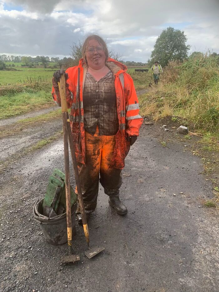 Woman in muddy work clothes holding tools outdoors, illustrating why girls don’t get their nails done with savage replies.