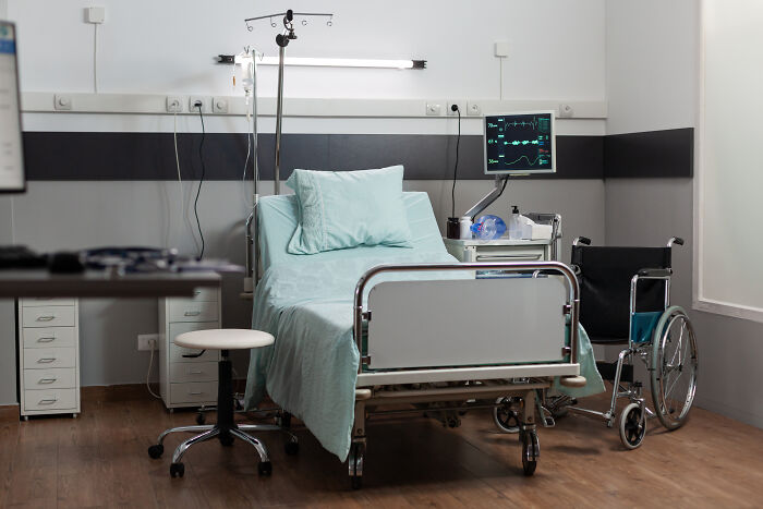 Empty hospital bed and wheelchair in a medical room, illustrating a setting related to anesthesia and patient care.