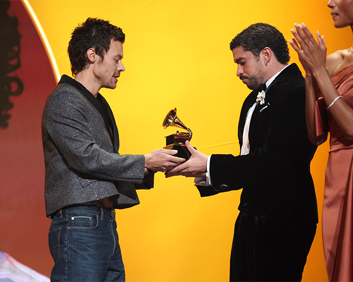 Harry Styles receiving a Grammy award on stage wearing a casual outfit during the 2026 Grammys ceremony.