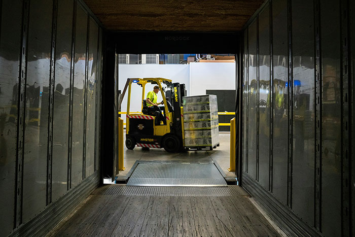 Forklift operator moving pallet in warehouse loading dock, illustrating fast coworker actions related to getting fired.