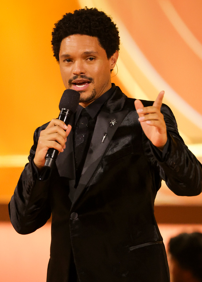 Trevor Noah speaking at Grammys event, wearing black suit, holding microphone during his bizarre Grammys statement.