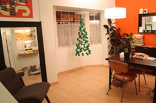Creative DIY Christmas tree made from hanging green ornaments in a modern living room.