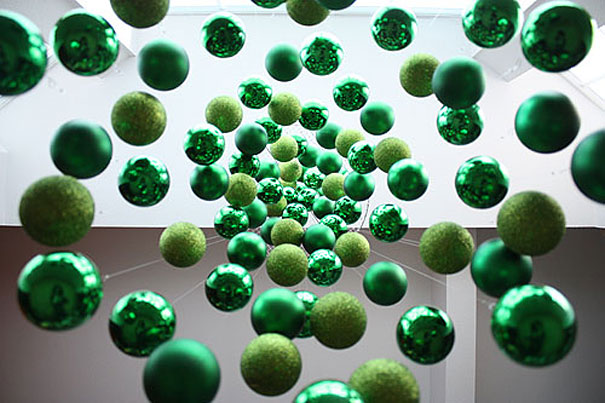 Hanging green ornaments forming a spiral, creating a DIY Christmas tree look.