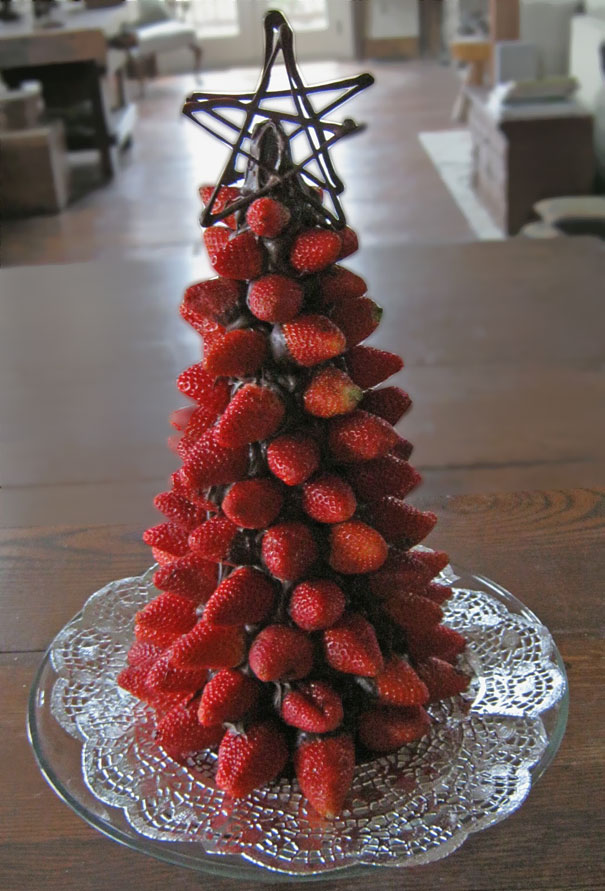 DIY Christmas tree made of stacked strawberries with a star topper on a glass plate.