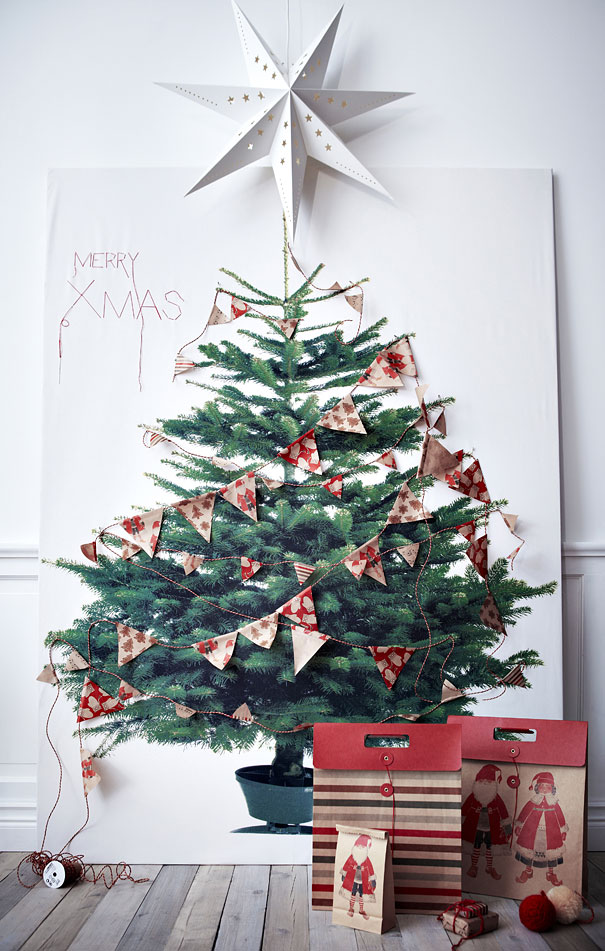 DIY Christmas tree art with paper bunting and star, festive gift bags nearby on wooden floor.