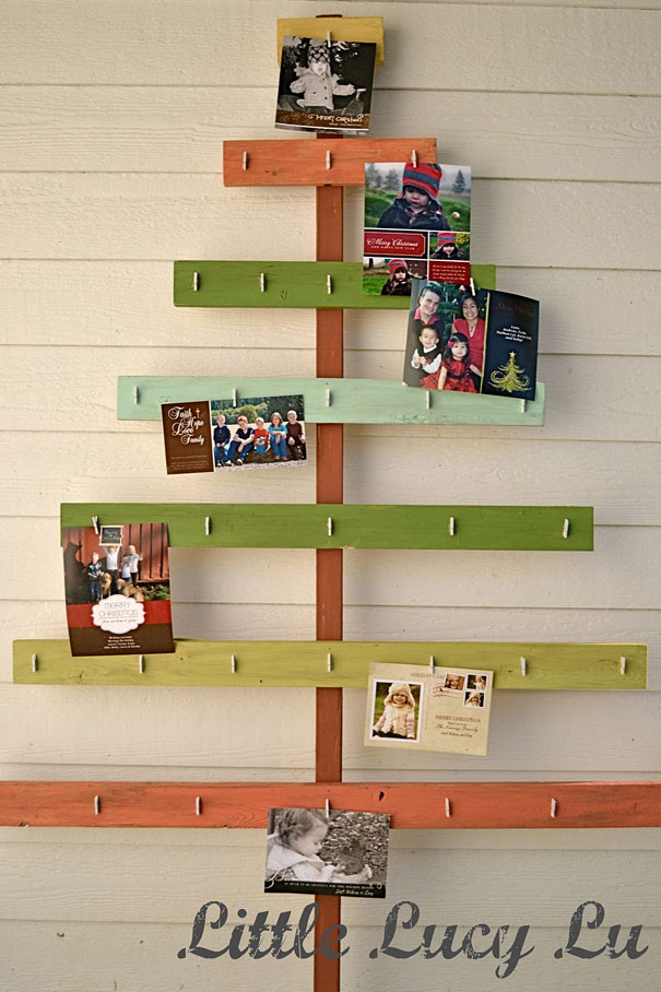 DIY Christmas tree made from colorful wooden planks, displaying holiday cards on a wall.
