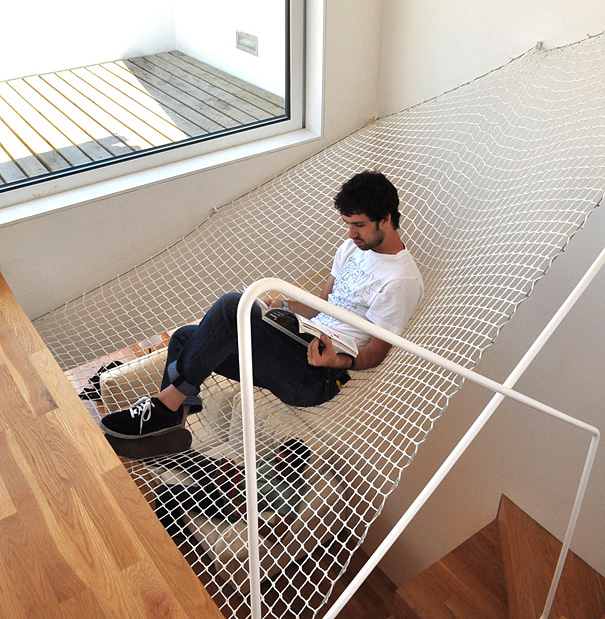 Man reading a book while sitting on an indoor hammock net, showcasing amazing design ideas for a modern house interior. Man reading a book while sitting on an indoor hammock net, showcasing amazing design ideas for a modern house interior.